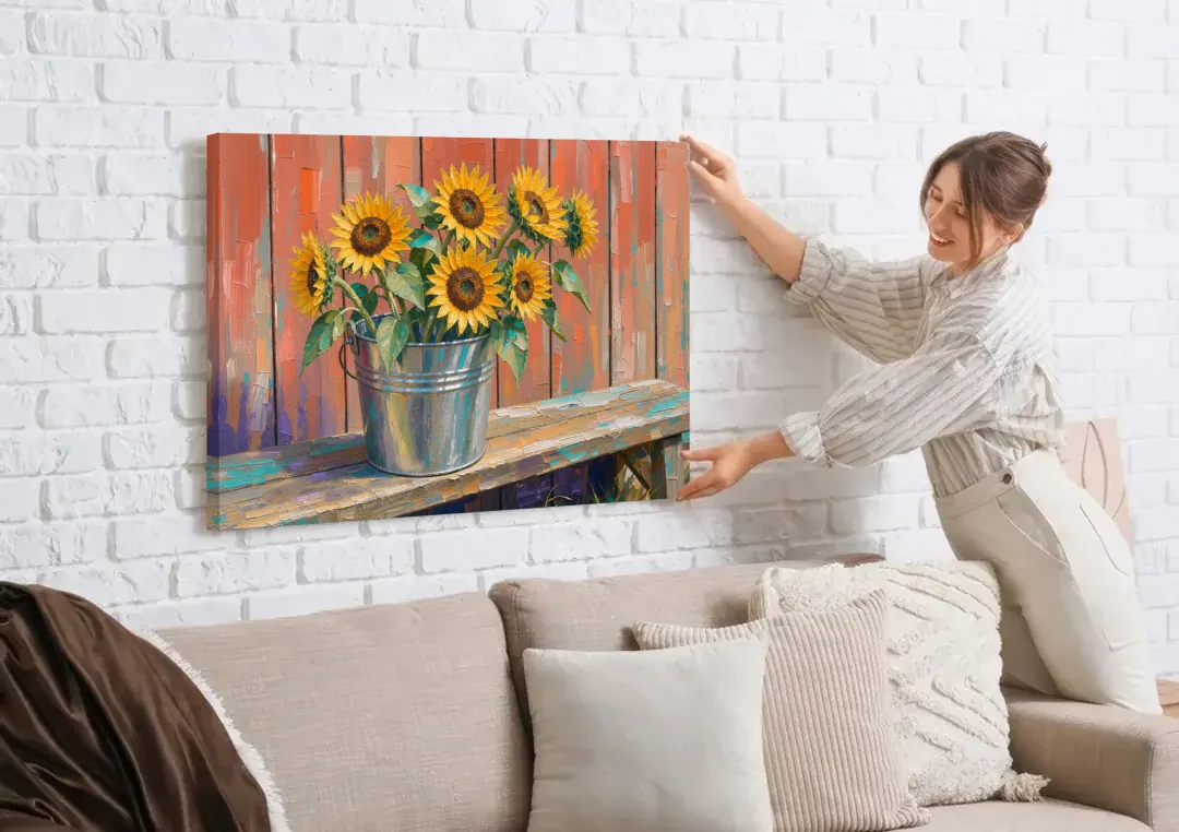 Rustic Sunflowers in a Tin Bucket canvas wall art being hung on a white brick wall above a sofa