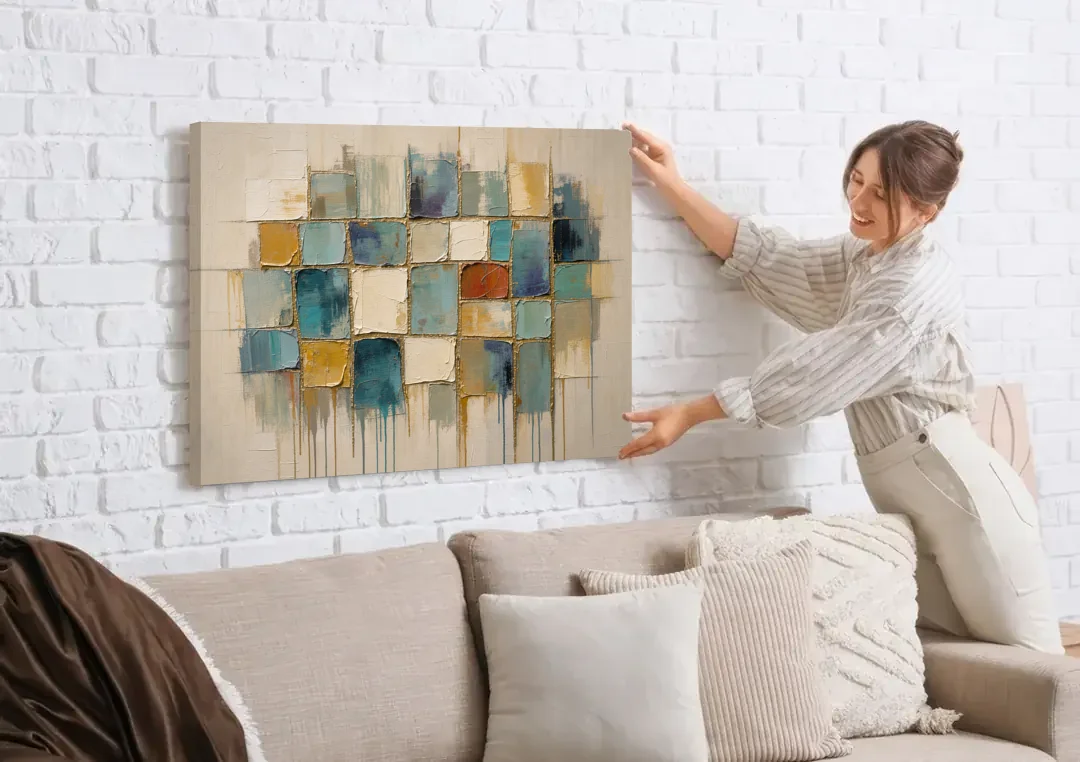 Teal and Cream Tile Grid with Gold Seams canvas wall art being hung on a white brick wall above a sofa