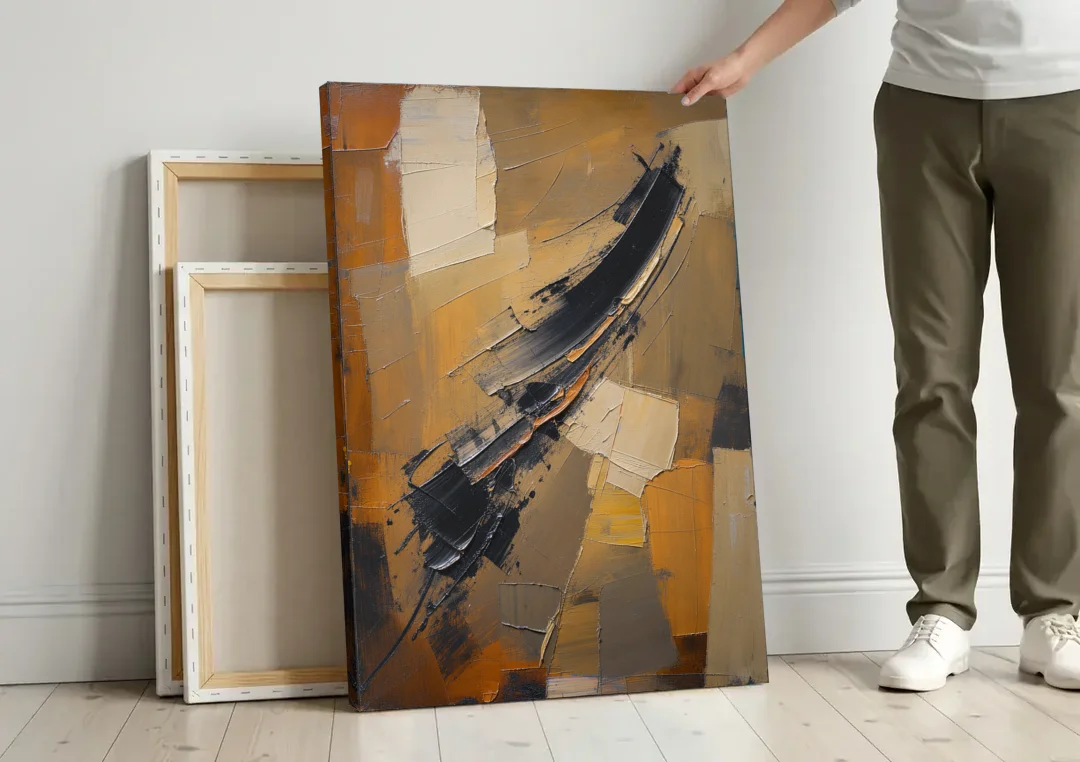 Textured Black Knife Sweep Over Ochre canvas wall art leaning against a wall next to blank canvases