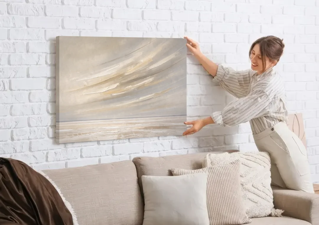 Textured Neutral Wall Art of Wind Streaks Over Flats canvas wall art being hung on a white brick wall above a sofa