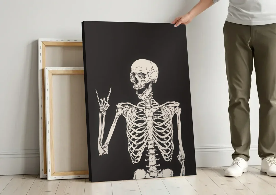 The Fun Halloween Skeleton canvas wall art leaning against a wall next to blank canvases