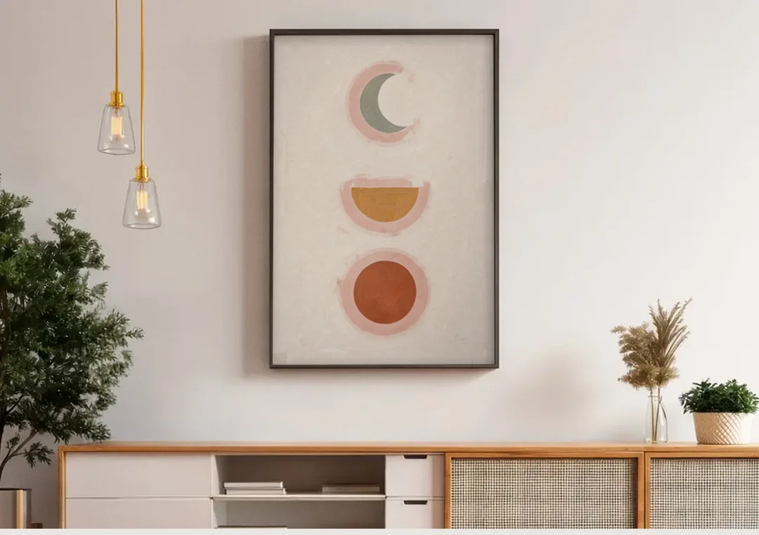 Three Moon Phases Stacked in Earth Tones canvas wall art above a wooden sideboard under pendant lights