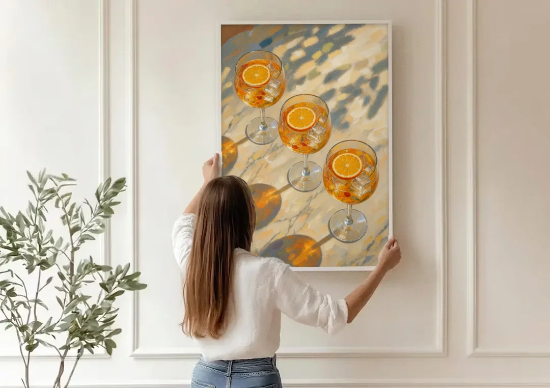Three Orange Spritz Glasses in Dappled Sunlight canvas wall art being hung on a paneled wall