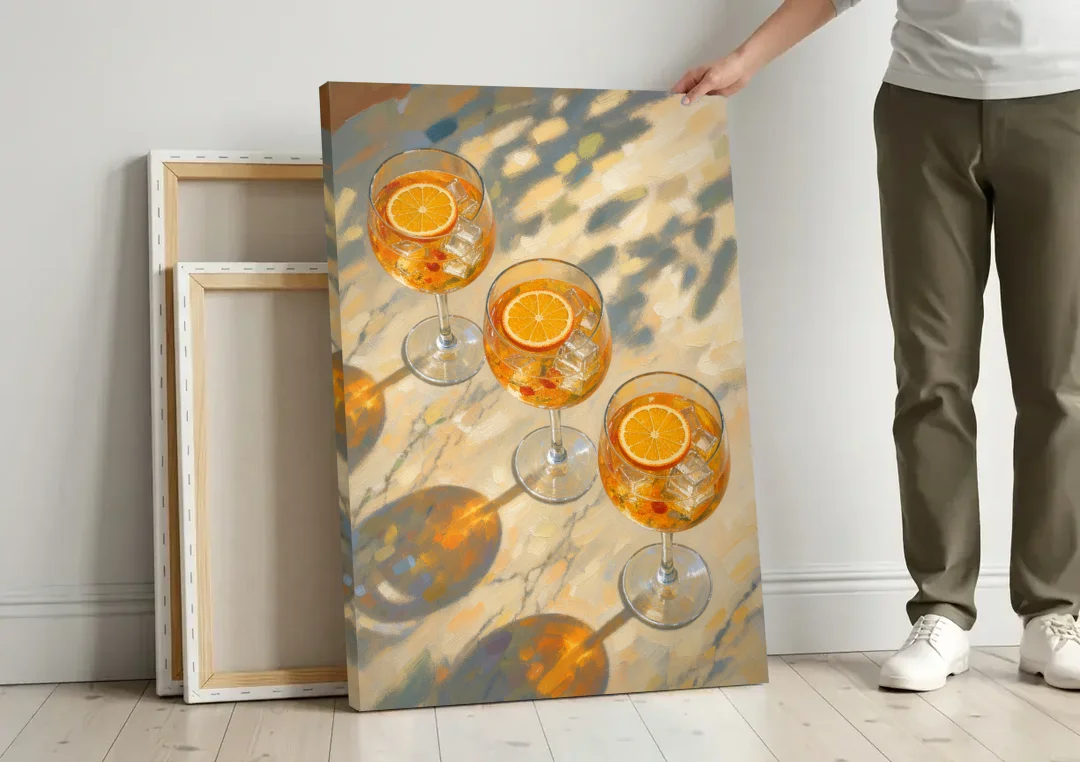 Three Orange Spritz Glasses in Dappled Sunlight canvas wall art leaning against a wall next to blank canvases