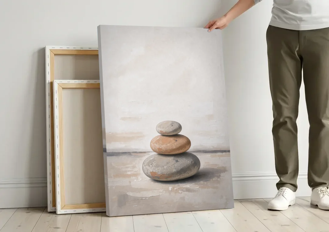 Three Stacked Stones on Pale Dusk Ground canvas wall art leaning against a wall next to blank canvases