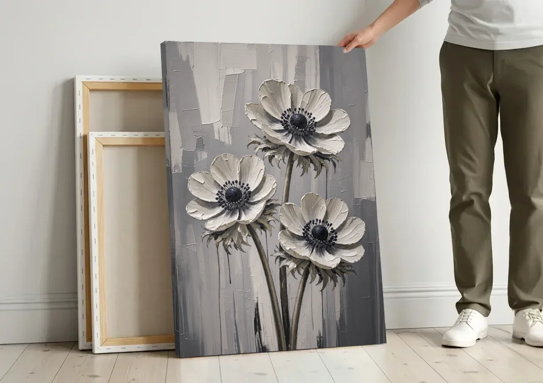 Three White Anemones with Black Centers canvas wall art leaning against a wall next to blank canvases