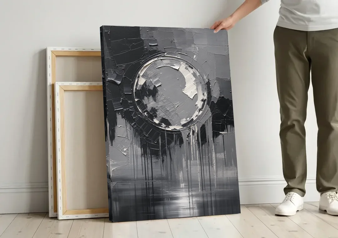 Torn Grey Circle Over Black Drips canvas wall art leaning against a wall next to blank canvases