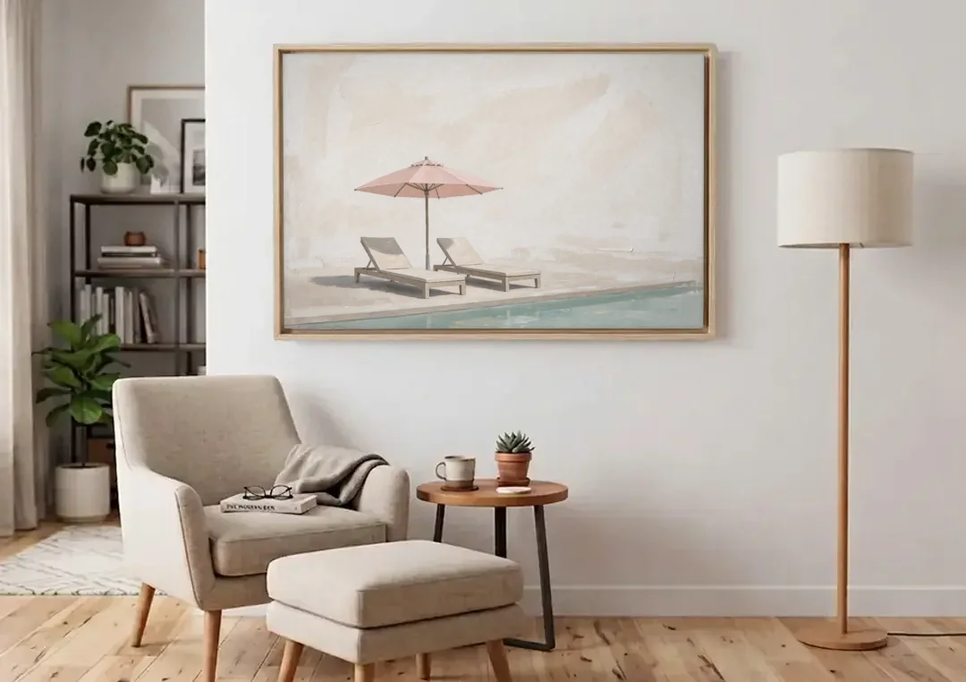 Two Chaise Longues Under a Pink Umbrella canvas wall art above an armchair in a bright living room