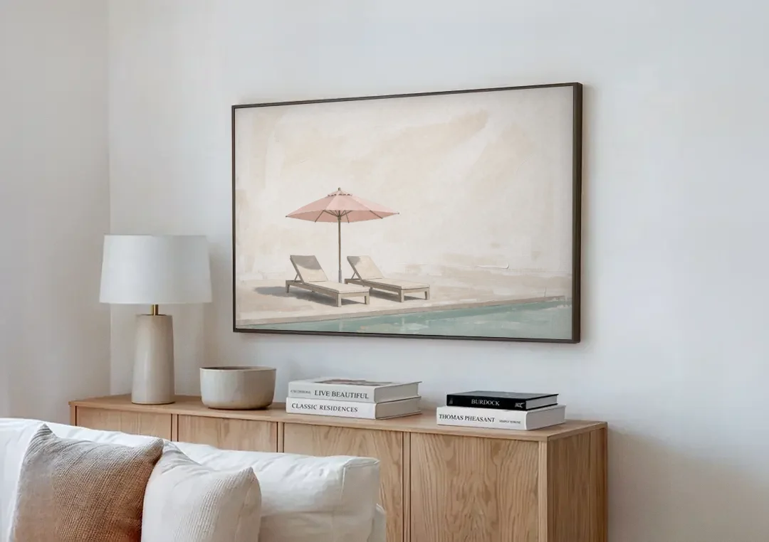 Two Chaise Longues Under a Pink Umbrella canvas wall art above a wooden sideboard next to a sofa