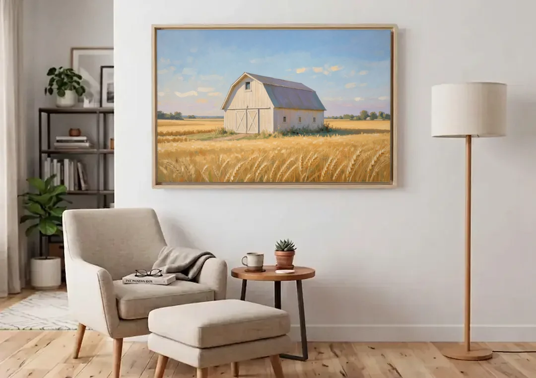 White Barn Beyond the Golden Wheat canvas wall art above an armchair in a bright living room