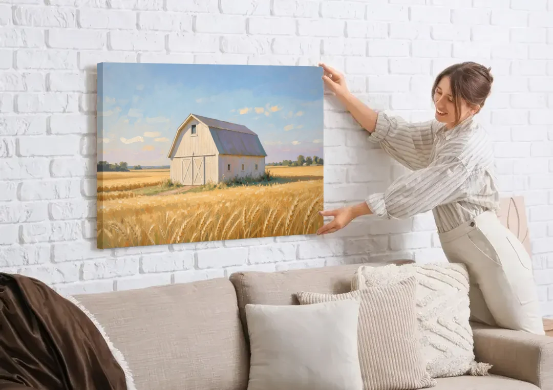 White Barn Beyond the Golden Wheat canvas wall art being hung on a white brick wall above a sofa