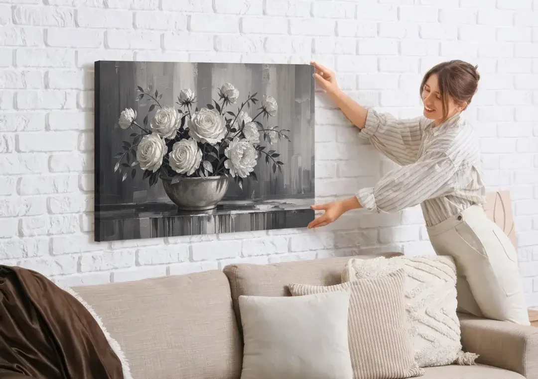 White Roses and Peonies in a Stoneware Bowl canvas wall art being hung on a white brick wall above a sofa