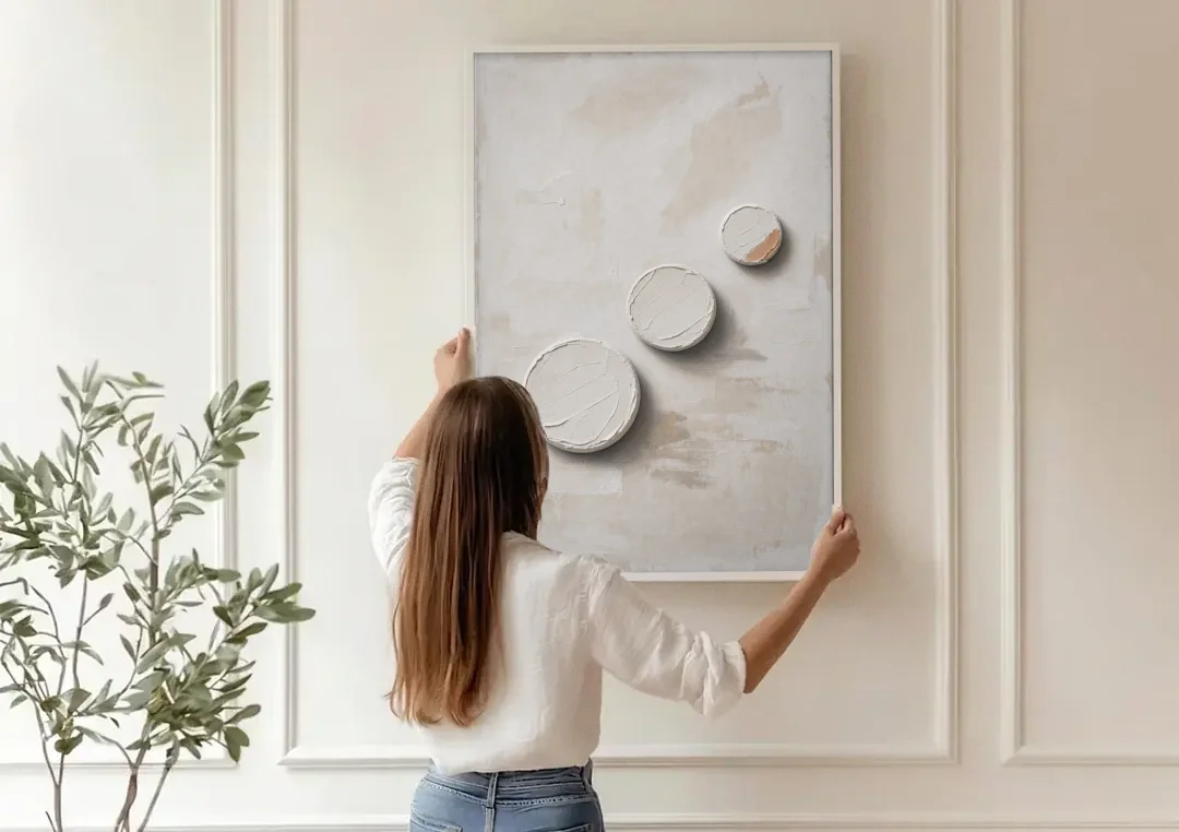 White Textured Wall Art of Three Rising Discs canvas wall art being hung on a paneled wall