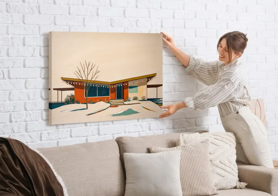 Winter Christmas Painting of a Butterfly Roof Ranch canvas wall art being hung on a white brick wall above a sofa