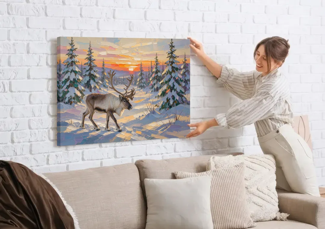 Winter Landscape Painting with a Lone Reindeer canvas wall art being hung on a white brick wall above a sofa