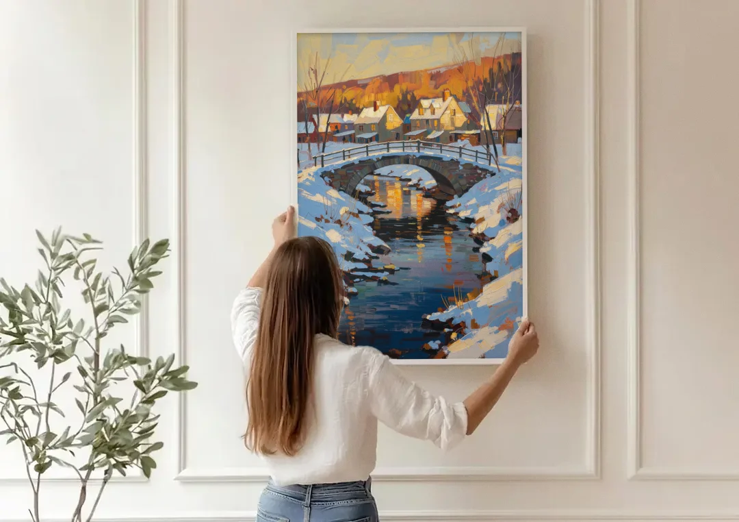 Winter Village Painting with Stone Footbridge canvas wall art being hung on a paneled wall
