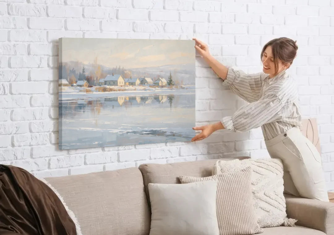 Winter Wonderland Wall Art by the Frozen Lake canvas wall art being hung on a white brick wall above a sofa