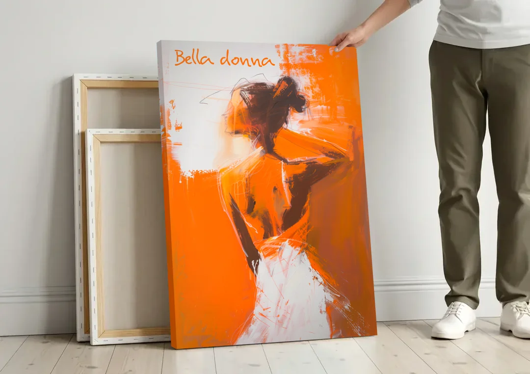 Woman Painting in Bold Orange Strokes canvas wall art leaning against a wall next to blank canvases