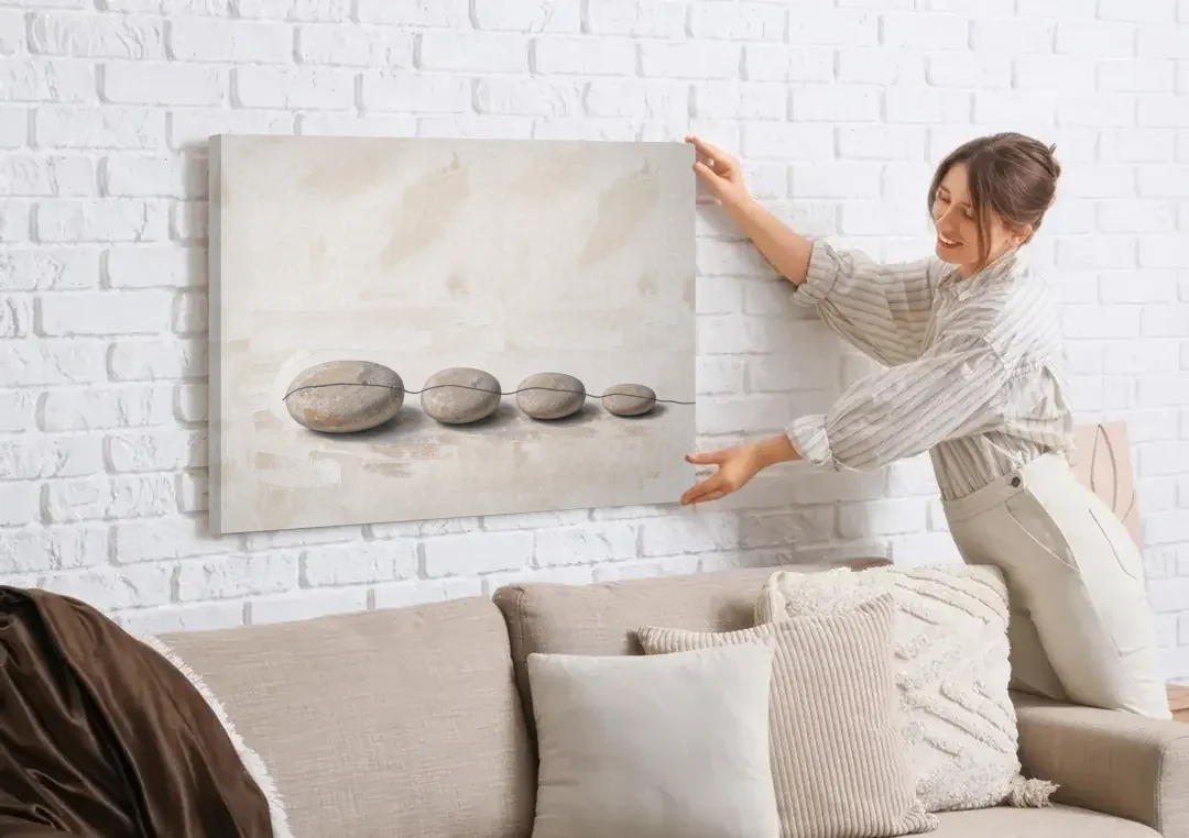 Zen Stones Painting on a Fine Thread canvas wall art being hung on a white brick wall above a sofa